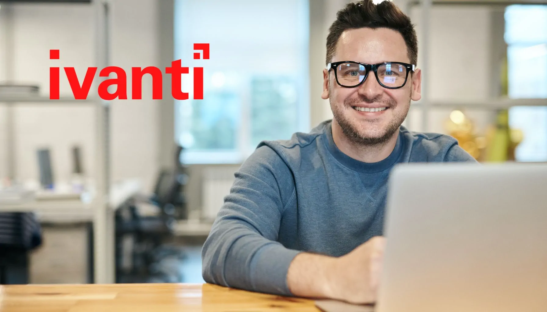 Mann am Laptop, Ivanti-Logo im Hintergrund