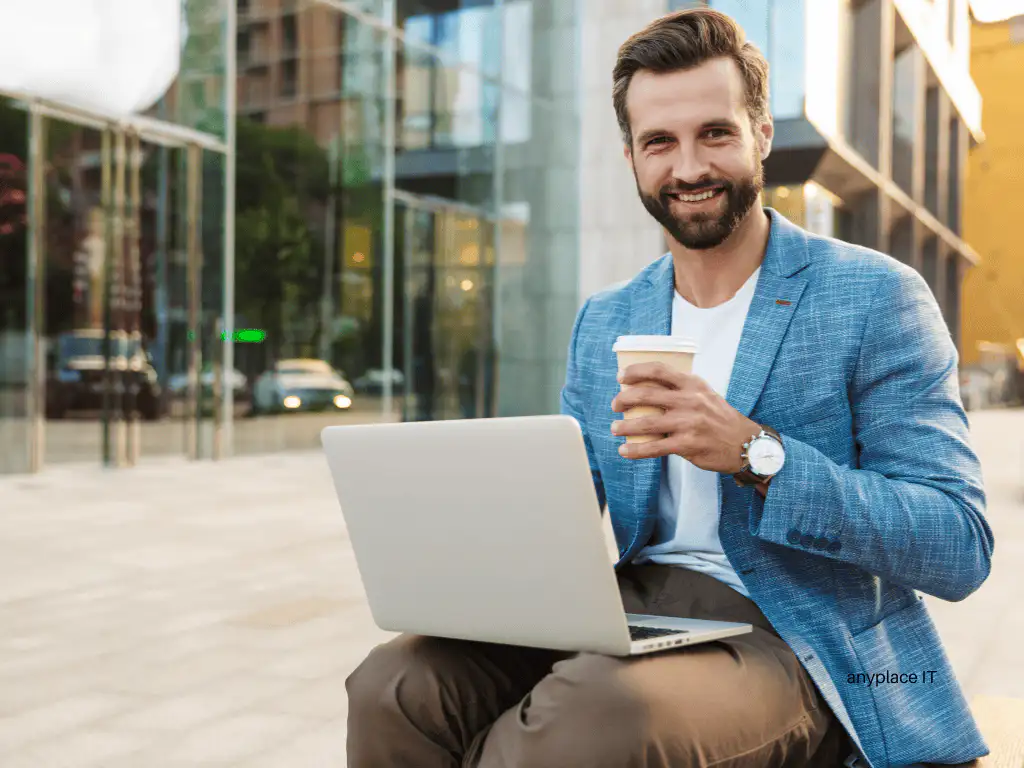 Mann mit Laptop und Kaffee draußen sitzen